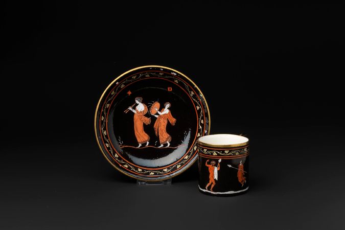 Tazza e piattino con scena bacchica a figure rosse su fondo nero