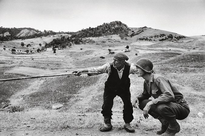 A Sicilian peasant shows an American officer the path taken by the Germans