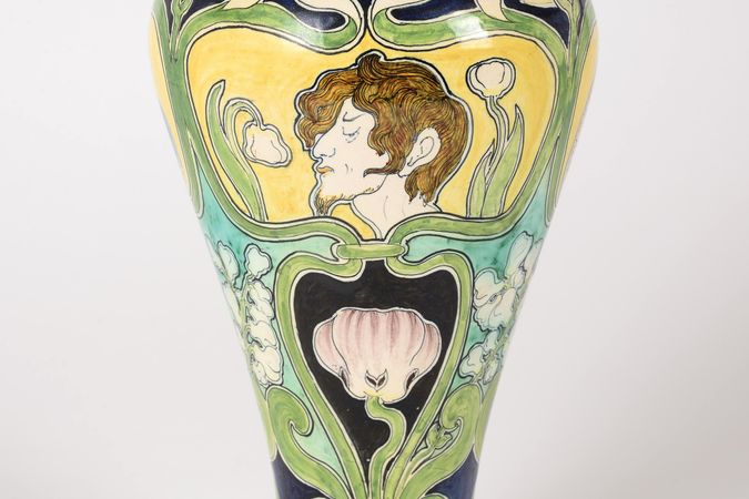 Vase mit weiblichen Gesichtern und Blumen