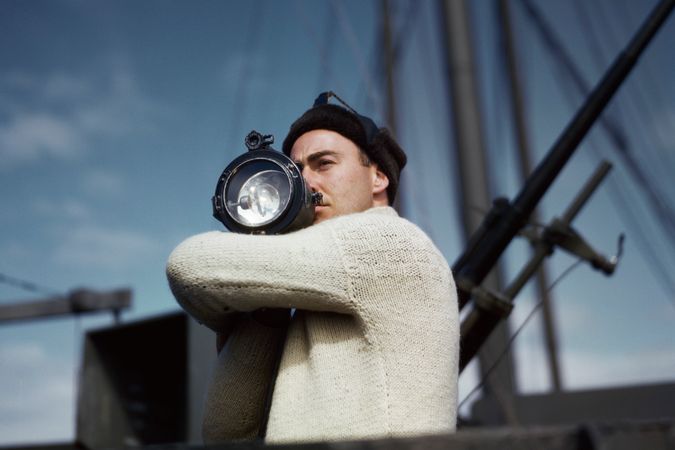Crew member signals to another ship of an allied convoy