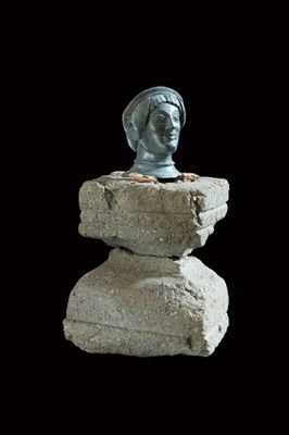 Cabeza femenina de bronce sobre base de piedra
