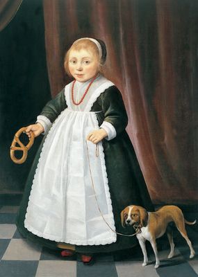 Portrait of a girl holding a pretzel with a dog by her side
