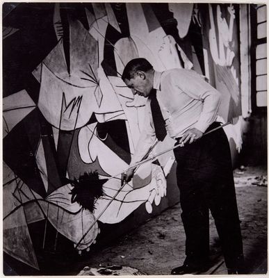 Picasso in piedi mentre lavora all'opera Guernica