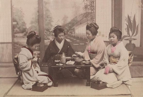 Gruppe japanischer Frauen in Kimonos um einen gedeckten Teetisch